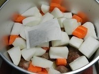 將炒好的牛肉放入電鍋的內鍋，然後放入切好的紅白蘿蔔